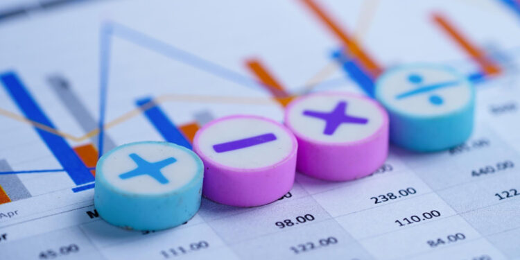 Four round buttons with math symbols (plus, minus, multiply, divide) are placed on a financial chart displaying colorful bar and line graphs with numbers and data in the background.