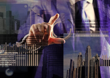 A person in a suit points at a virtual screen displaying digital graphs, charts, and financial data, overlaid on a city skyline with tall buildings in the background.